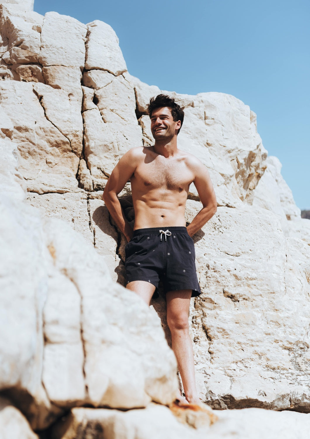 shorts de bain homme sur trentenaire torse nu devant un mur de calcaire en provence